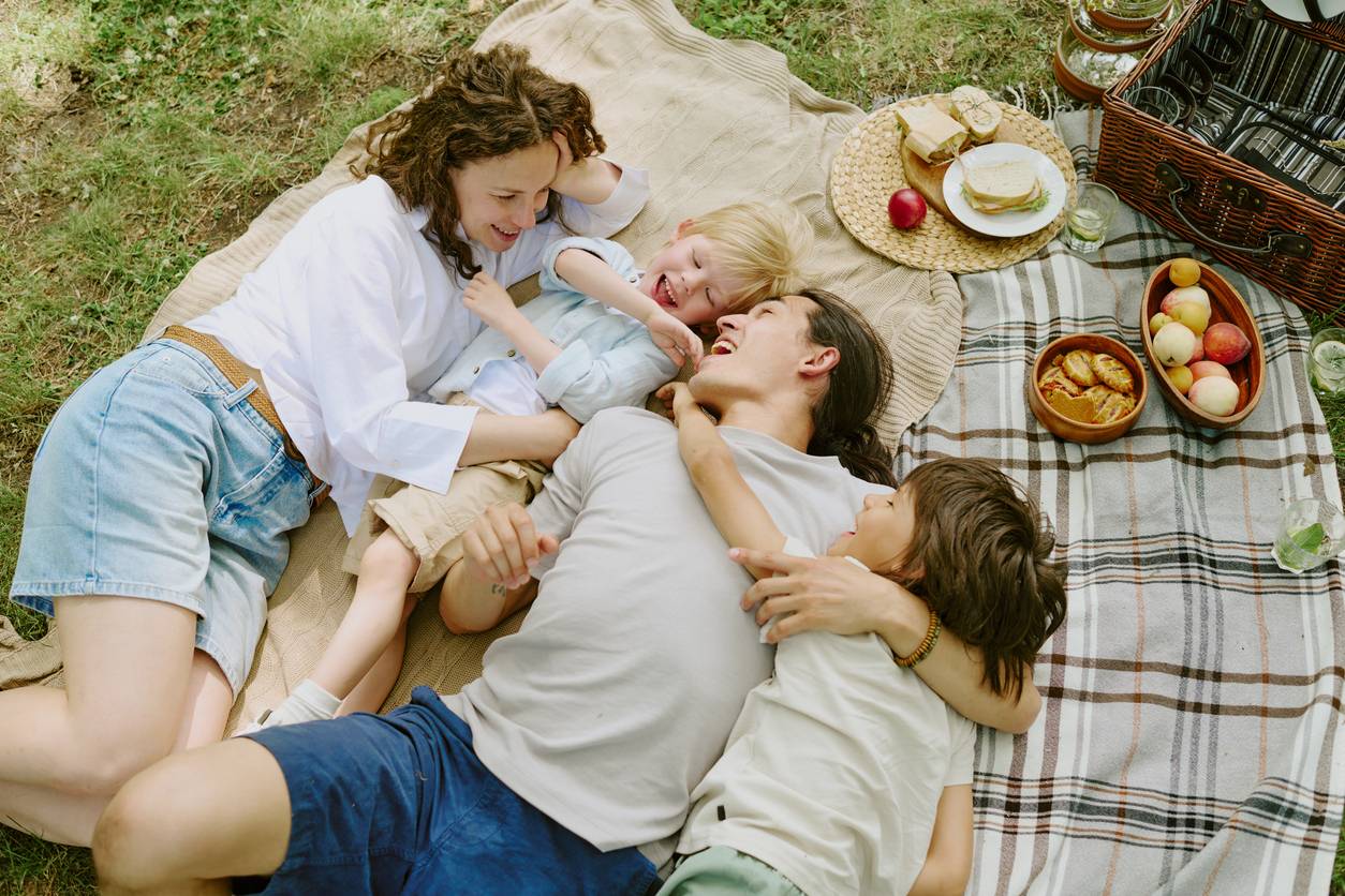 Famille installée sur une couverture sous un arbre avec bébé et panier pique-nique